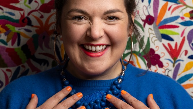 Head and shoulders portrait of a woman smiling against a patterned background