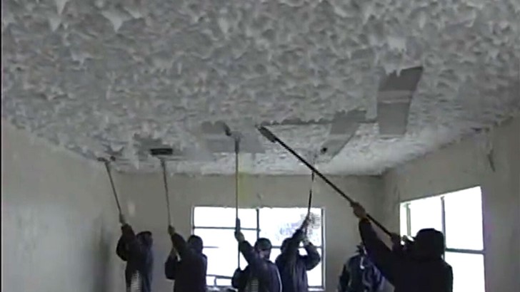 A still from low quality found footage shows a group scraping material off a ceiling