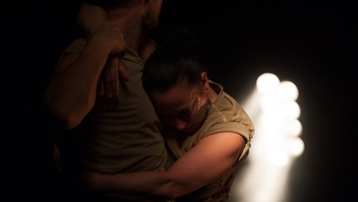 The dance duo White and Givan embrace in semi-darkness