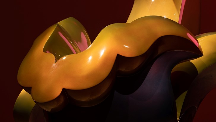 A gold and pink undulating abstract sculpture, pictured in close up