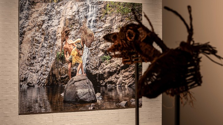 Two straw masks displayed against a photo of a rocky landscape