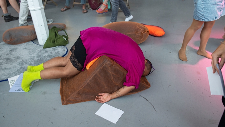 A man lies face down on top of an oddly shaped cushion