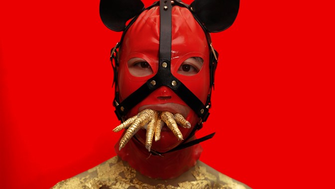 The performers Wei Zhang poses in a striking red mask