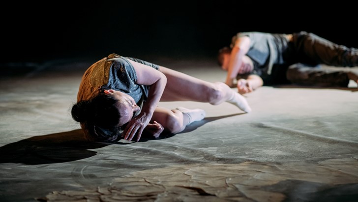 Two dancers lie on a stage