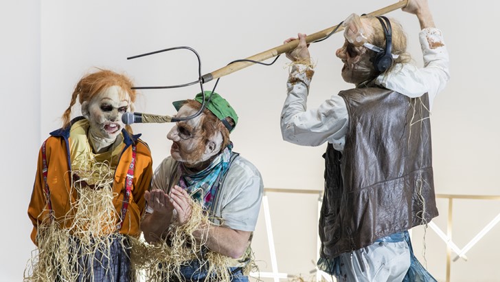 A group of performers in unsettling masks 