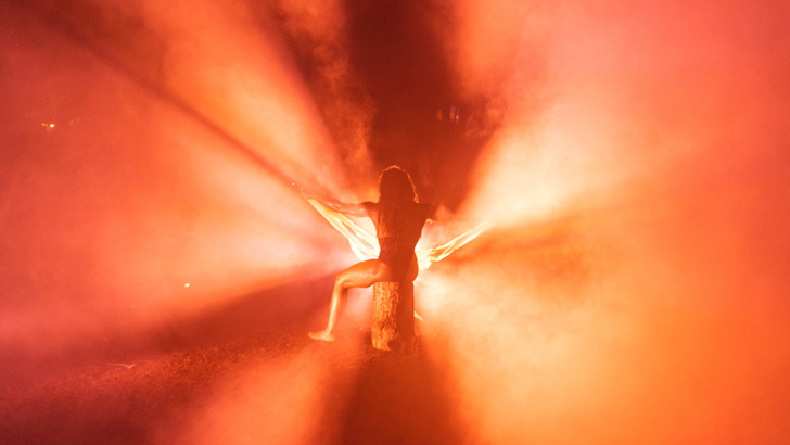 A silhouetted figure pictured against orange and gold light