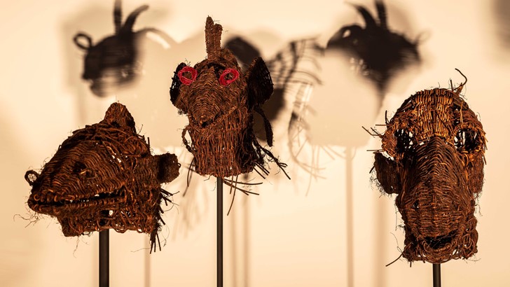 A close up of straw masks displayed in a gallery space