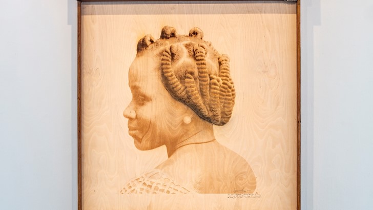 A head and shoulders portrait of a woman, printed on and framed in wood