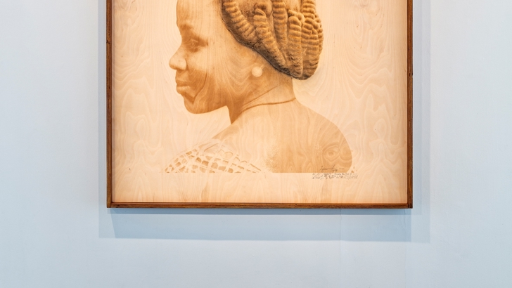 A head and shoulders portrait of a woman, printed on and framed in wood